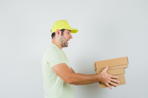 Hombre joven con gorra de camiseta entregando cajas de cartón