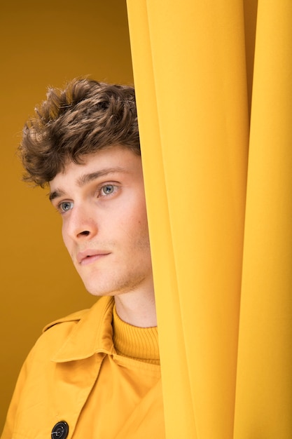 Foto gratuita hombre joven y guapo al lado de una cortina en un escenario amarillo