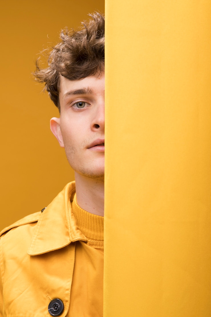 Foto gratuito hombre joven y guapo al lado de una cortina en un escenario amarillo
