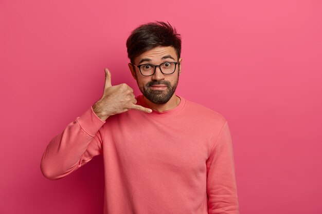 Hombre joven guapo con barba hace gesto de teléfono