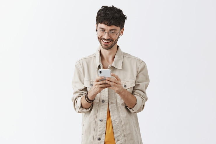 Foto gratuito hombre joven guapo emocionado con teléfono móvil y mirando feliz