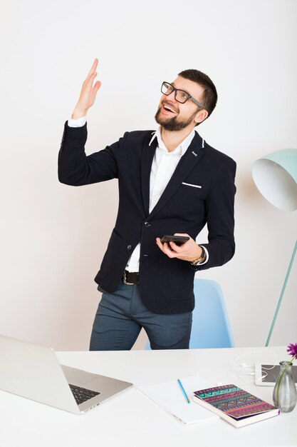 Hombre joven guapo con estilo hipster en chaqueta joven en la mesa de oficina