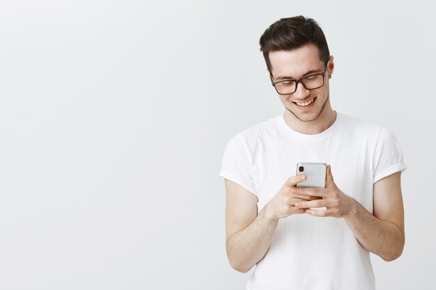 Hombre joven guapo con gafas mediante teléfono móvil