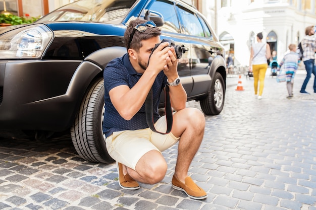 Hombre joven guapo hipster caminando con cámara de fotos en la calle de la ciudad vieja