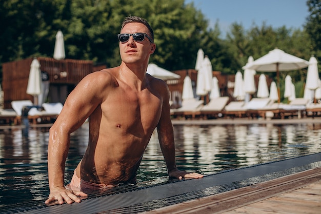 Hombre joven guapo saliendo de la piscina