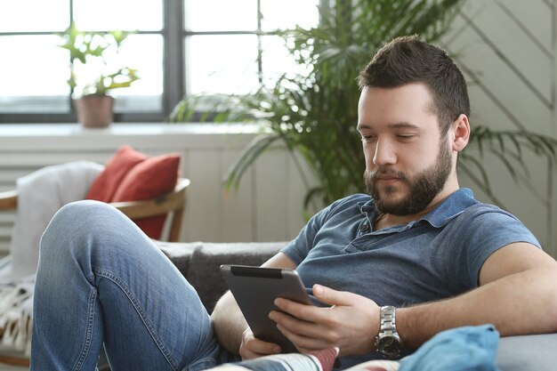 Hombre joven guapo con tableta digital o libro electrónico