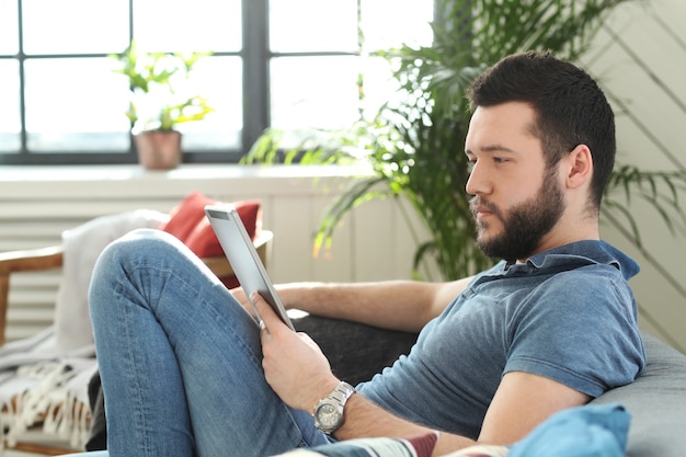 Hombre joven guapo con tableta digital o libro electrónico