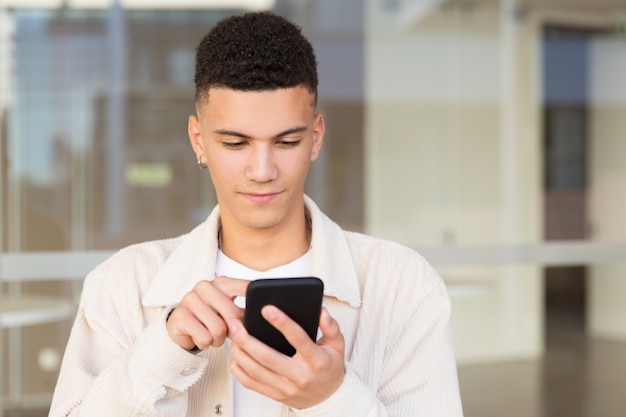 Hombre joven guapo con teléfono inteligente al aire libre