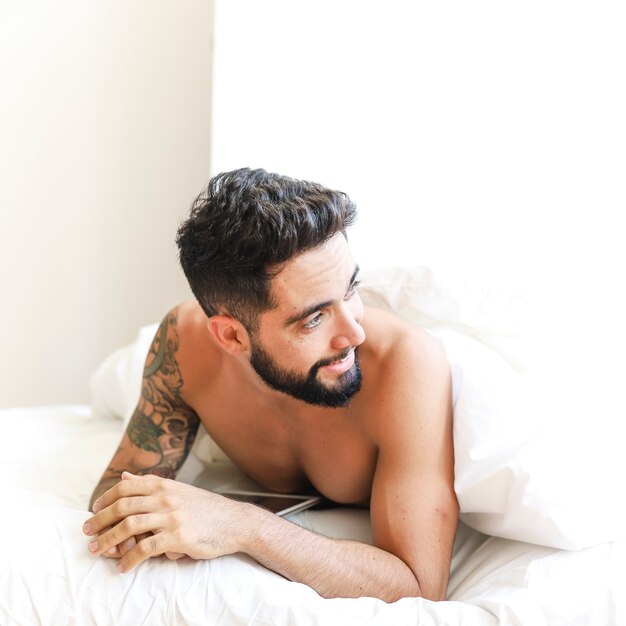 Foto gratuita hombre joven hermoso que miente en cama