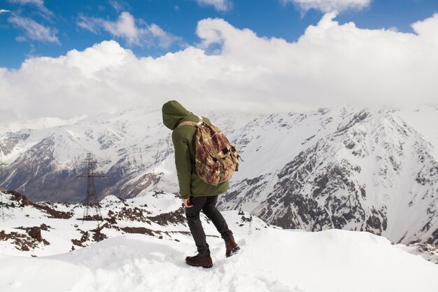 Hombre joven inconformista senderismo en las montañas, viajes de vacaciones de invierno