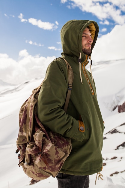Hombre joven inconformista senderismo en las montañas, viajes de vacaciones de invierno