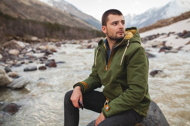 Hombre joven inconformista senderismo por el río, naturaleza salvaje, vacaciones de invierno