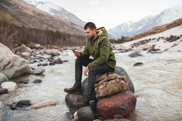 Foto gratuita hombre joven inconformista con smartphone, naturaleza salvaje, vacaciones de invierno, senderismo