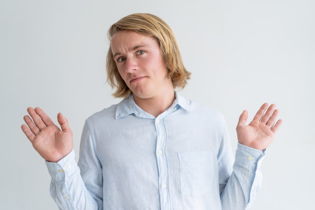 Foto gratuita hombre joven insatisfecho que levanta las manos y que mira la cámara