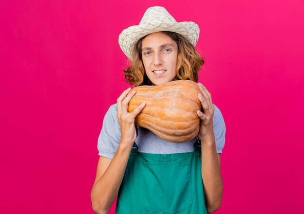 Hombre joven jardinero vestido con mono y sombrero con calabaza