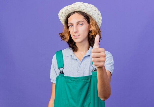 Hombre joven jardinero vestido con mono y sombrero