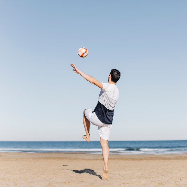 Foto gratuita hombre joven jugando al fútbol en la playa