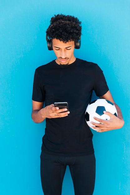 Hombre joven juguetón que sostiene y que usa el teléfono