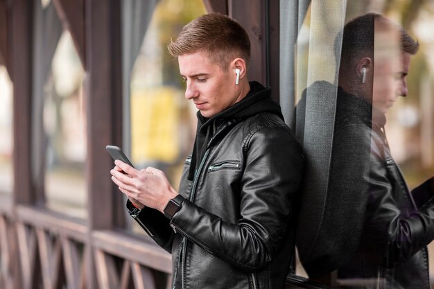 Hombre joven de lado escuchando música con auriculares afuera