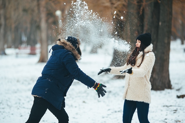 Hombre joven lanzando una bola de nieve a su amiga