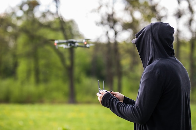 Hombre joven con máscara usa control remoto para drone en paisaje natural