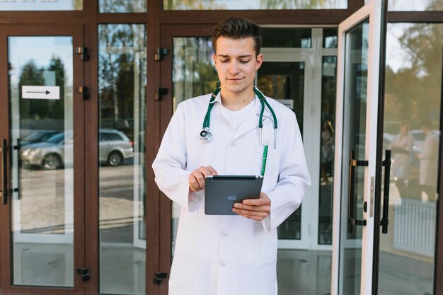 Hombre joven médico con tableta en el hospital