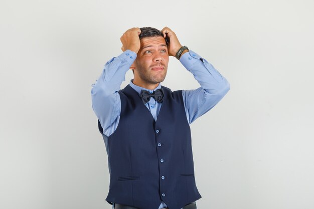 Hombre joven mirando hacia arriba con las manos en la cabeza en traje y mirando estresante.