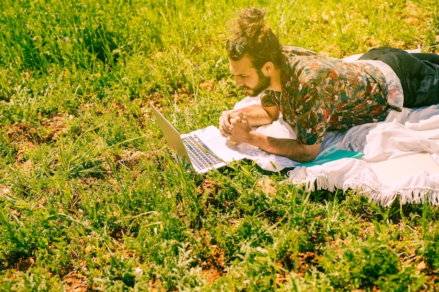 Foto gratuita hombre joven mirando portátil en aire libre