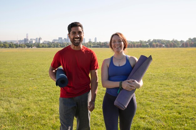 Hombre joven y mujer al aire libre con colchonetas de yoga
