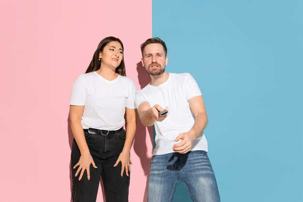 Hombre joven, mujer en casual sobre fondo bicolor rosa, azul.