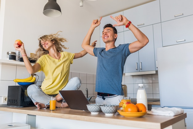 Hombre joven y mujer enamorada divirtiéndose saludable desayuno en la cocina por la mañana