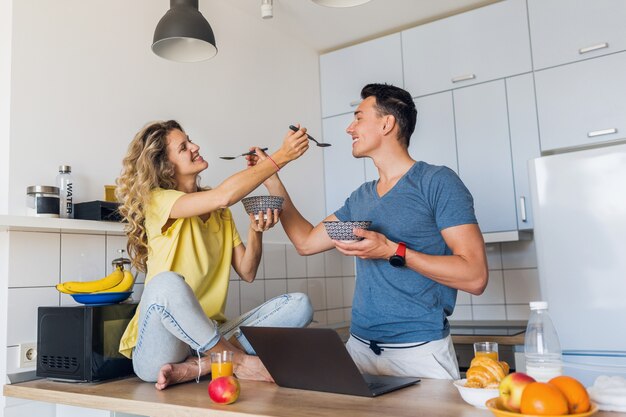 Hombre joven y mujer enamorada divirtiéndose saludable desayuno en la cocina por la mañana