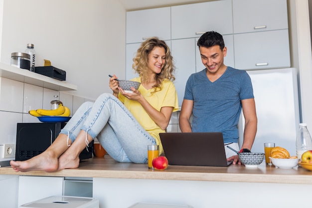 Hombre joven y mujer enamorada divirtiéndose saludable desayuno en la cocina por la mañana