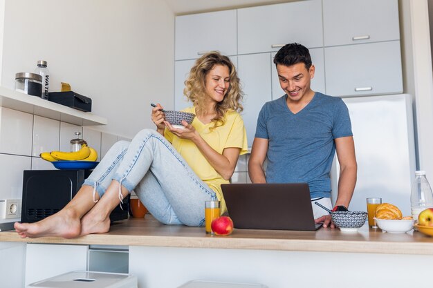 Hombre joven y mujer enamorada divirtiéndose saludable desayuno en la cocina por la mañana