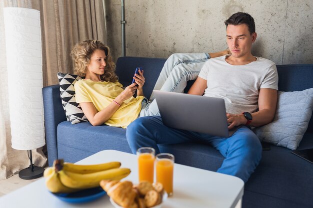 Hombre joven y mujer enamorada sentados en casa trabajando en línea