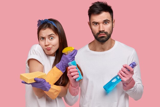 Hombre joven y mujer posando con productos de limpieza