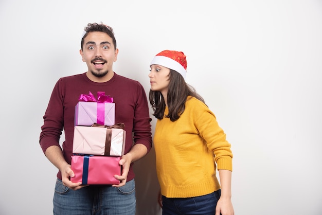 Hombre joven con mujer posando con regalos de Navidad.