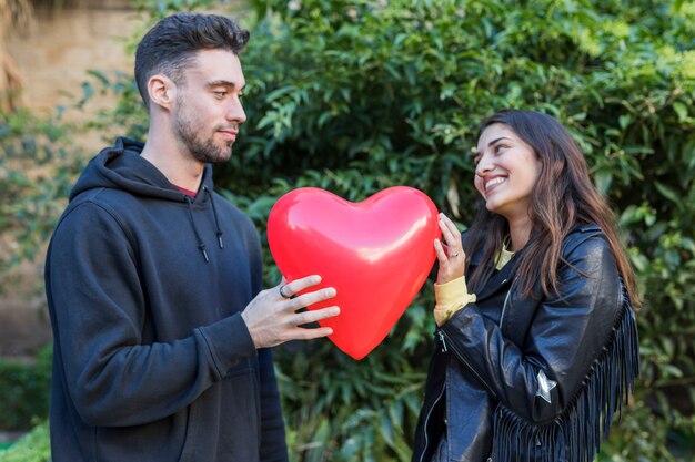 Hombre joven y mujer sonriente con globo en forma de corazón
