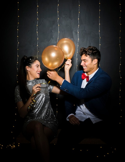 Foto gratuita hombre joven y mujer sonrientes con los globos en banco