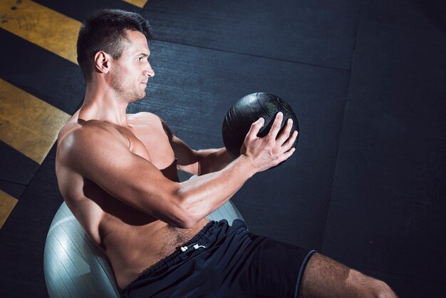 Hombre joven muscular que ejercita con la bola de medicina