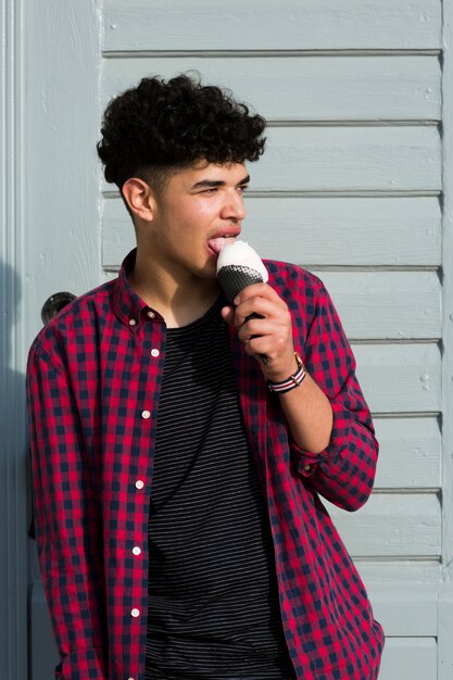Hombre joven negro comiendo helado en camisa a cuadros