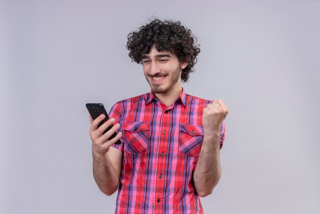 Hombre joven pelo rizado aislado camisa colorida smartphone puño sí