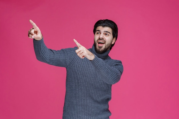 Foto gratuita hombre joven con pelos largos y barba mostrando o apuntando a algo con los dedos.