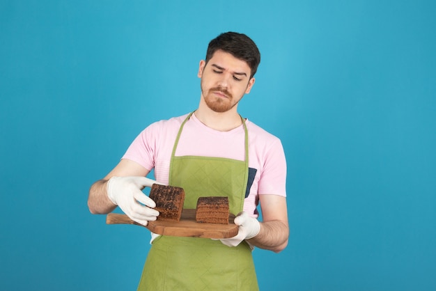 Foto gratuita hombre joven pensativo que controla las rebanadas de pastel.