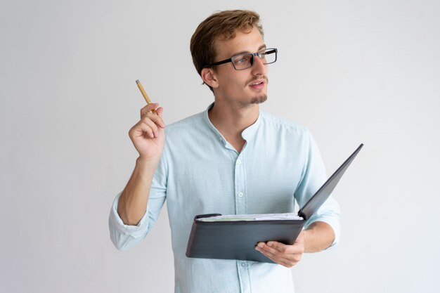 Hombre joven pensativo que sostiene el archivo, pluma y tener idea