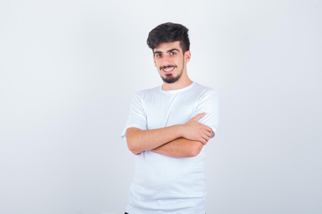 Hombre joven de pie con los brazos cruzados en camiseta y mirando confiado