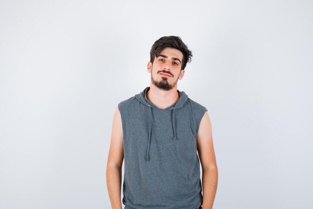 Hombre joven de pie con la espalda recta y posando a la cámara en camiseta gris y mirando serio