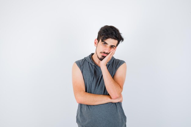 Hombre joven de pie en pose de pensamiento en camisa gris y mirando pensativo