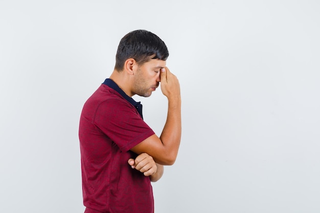 Hombre joven de pie en pose de pensamiento en camiseta y mirando indeciso. .