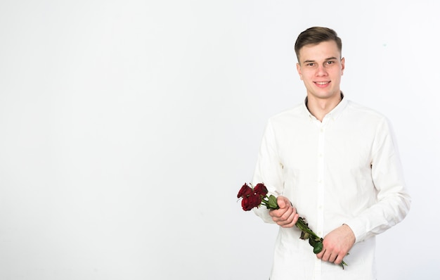 Hombre joven de pie con ramo de rosas